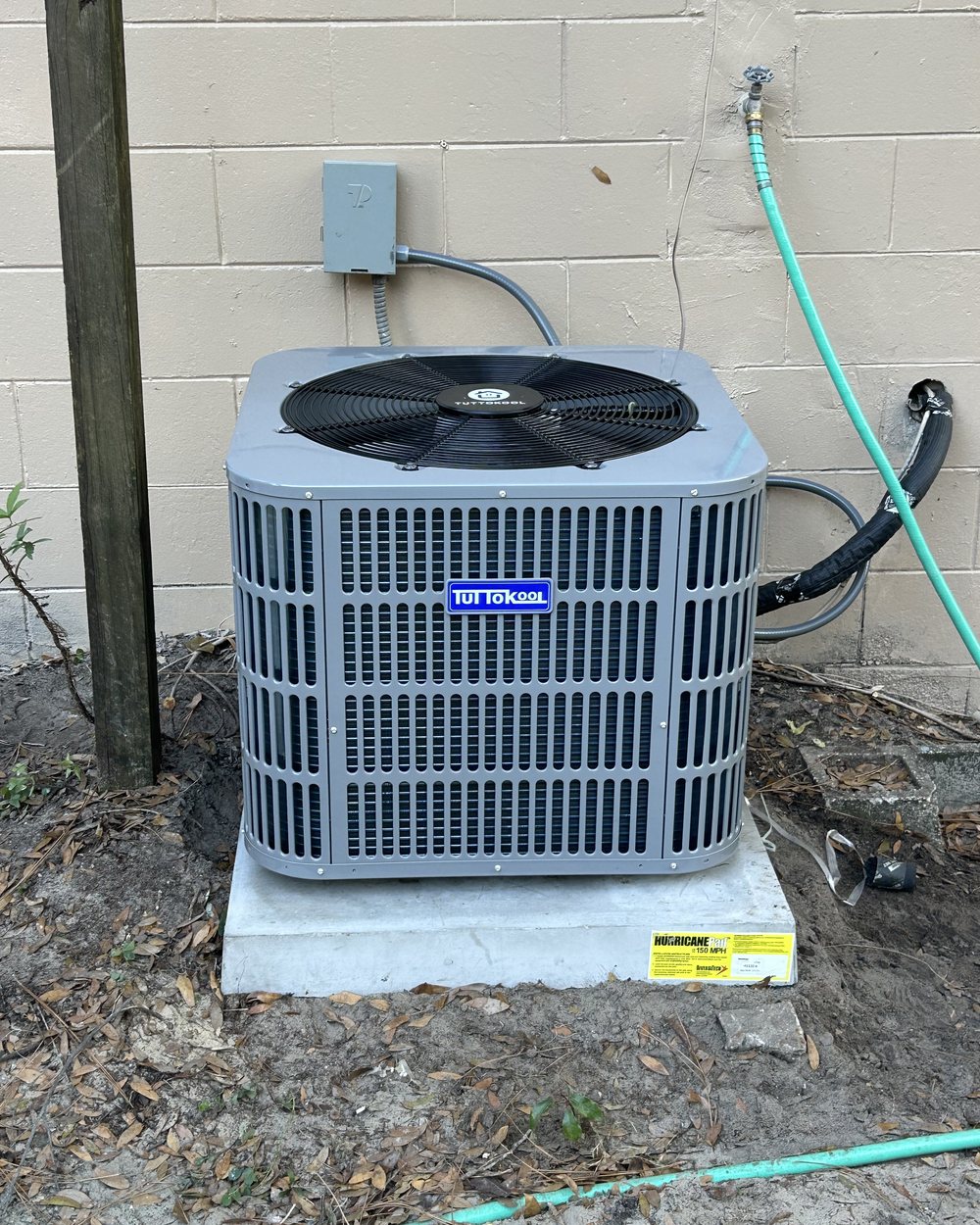 New condenser set on a fresh pad beside a home